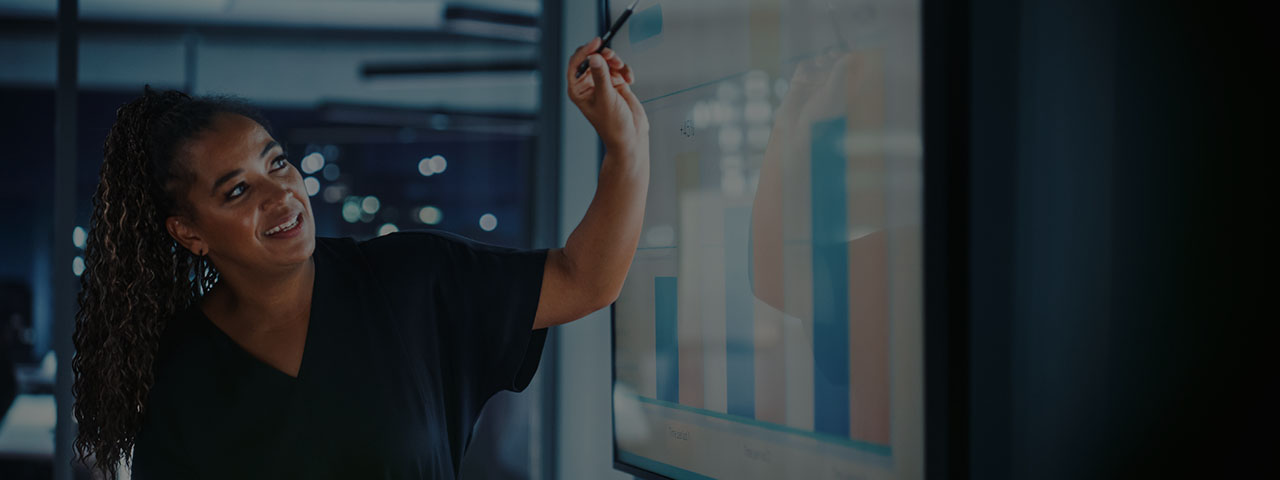 Businesswoman standing pointing at charts on a screen