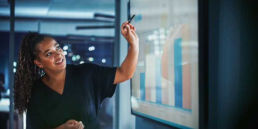 Businesswoman standing pointing at charts on a screen