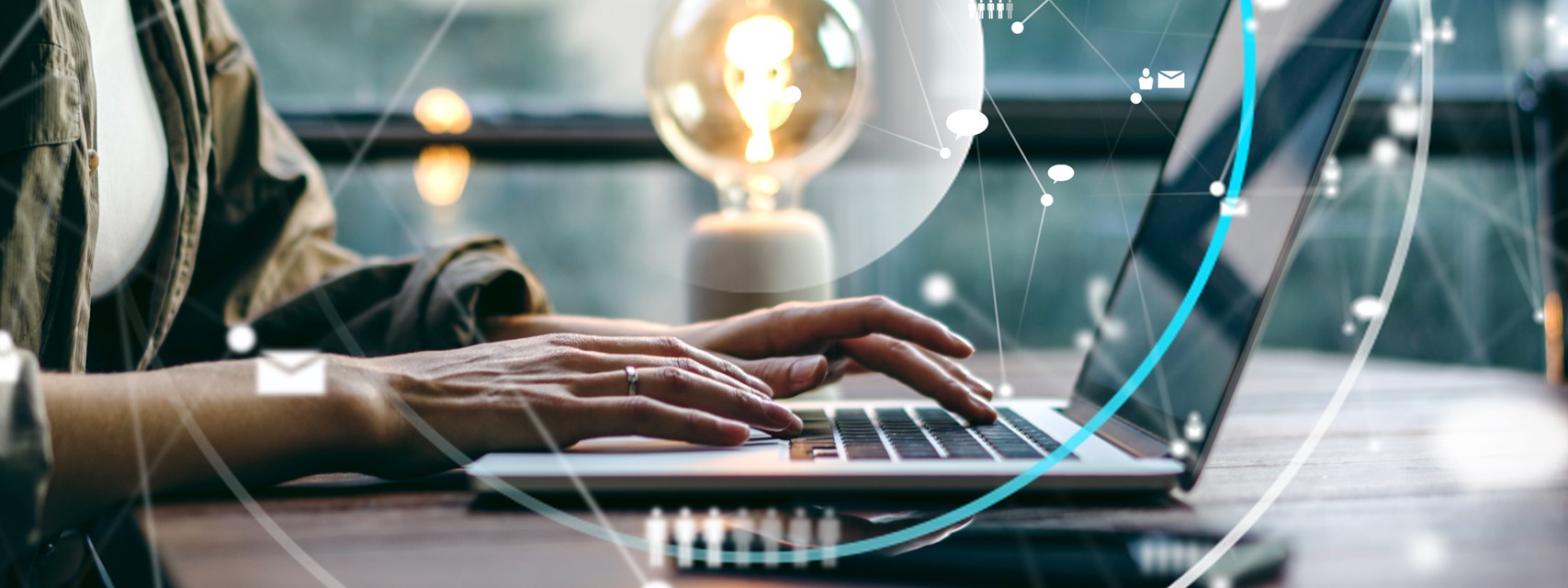 Woman typing on laptop with lightbulb in background.