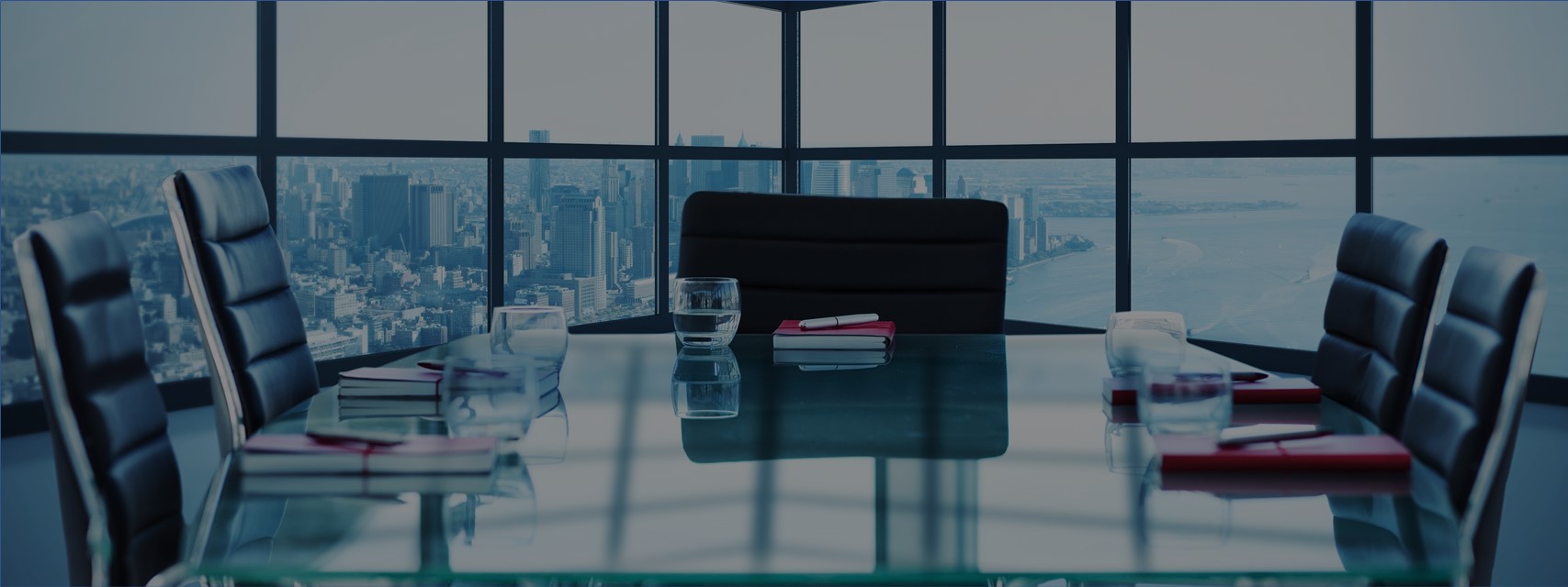 Image of a boardroom with NY cityscape seen in background through large window.
