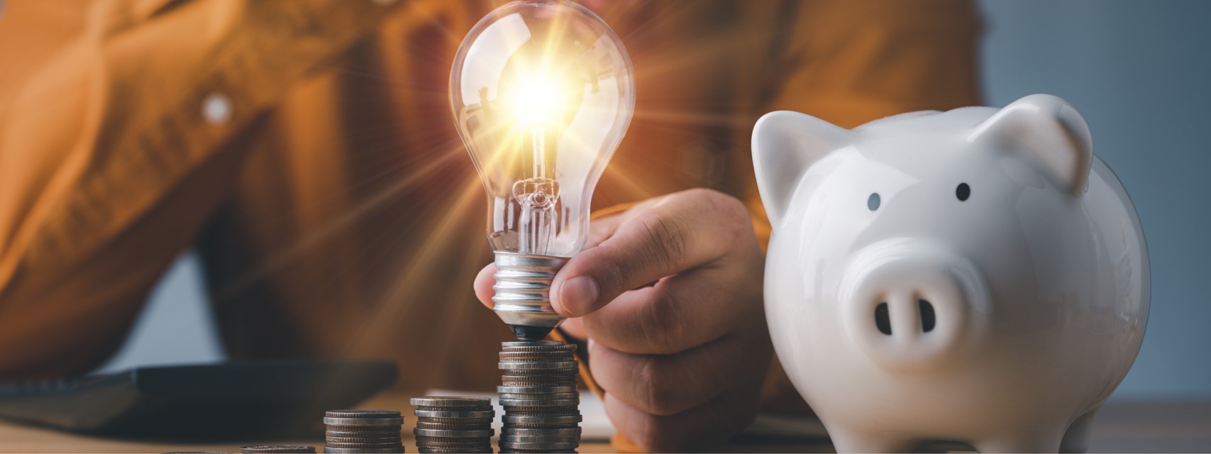 Light bulb with stack of coins and a piggy bank