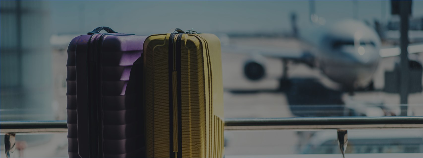 Two suitcases in the airport departure lounge, airplane in the background