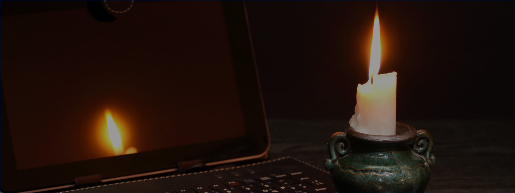 Picture of a Stock Plan Admin with a laptop with a candle during a blackout