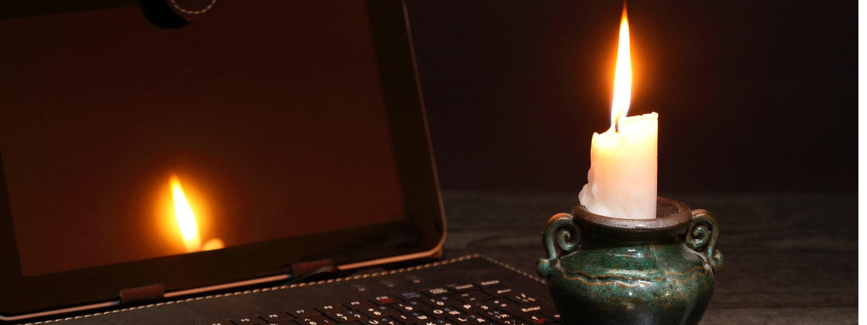 Picture of a laptop with a candle during a blackout