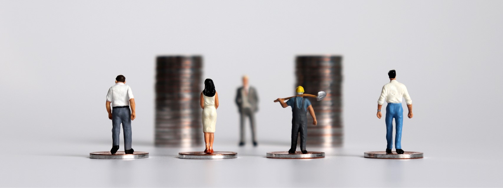 Miniature people with piles of coins to illustrate the concept of wealth creation for all workers.