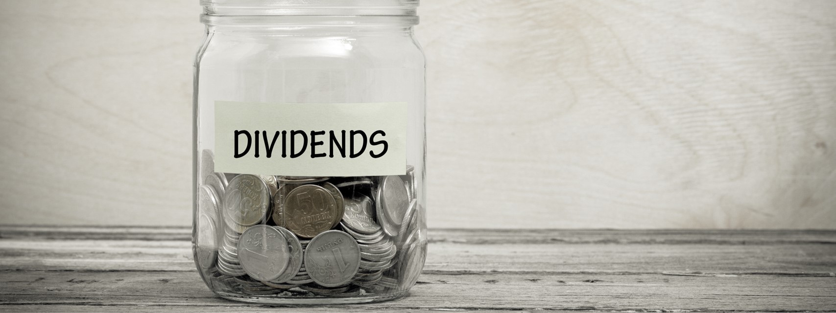 Glass jar filled with coins and labelled "Dividends"