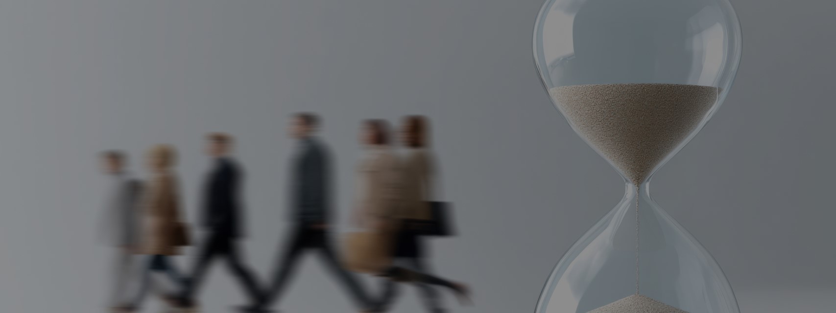 Hourglass with sand running down, motion blur of business people walking away in background