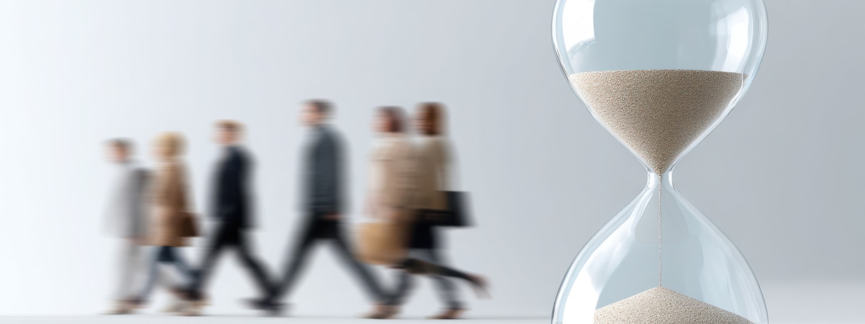 Hourglass with sand running down, motion blur of business people walking away in background