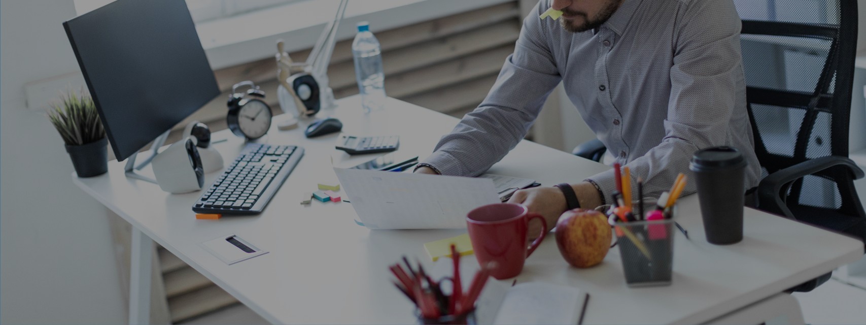 Investor reviewing a company's cap table - A young man in the office sits at a table, holds a cap from the marker in his mouth and works with documents.