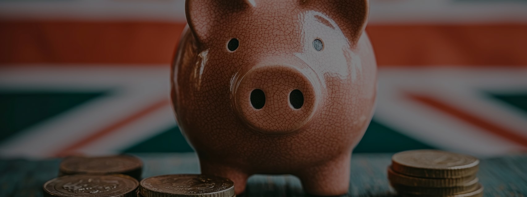 Piggy bank with UK coins and Union Jack in background