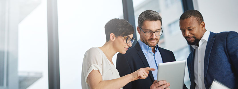 Three colleagues reviewing content on a tablet