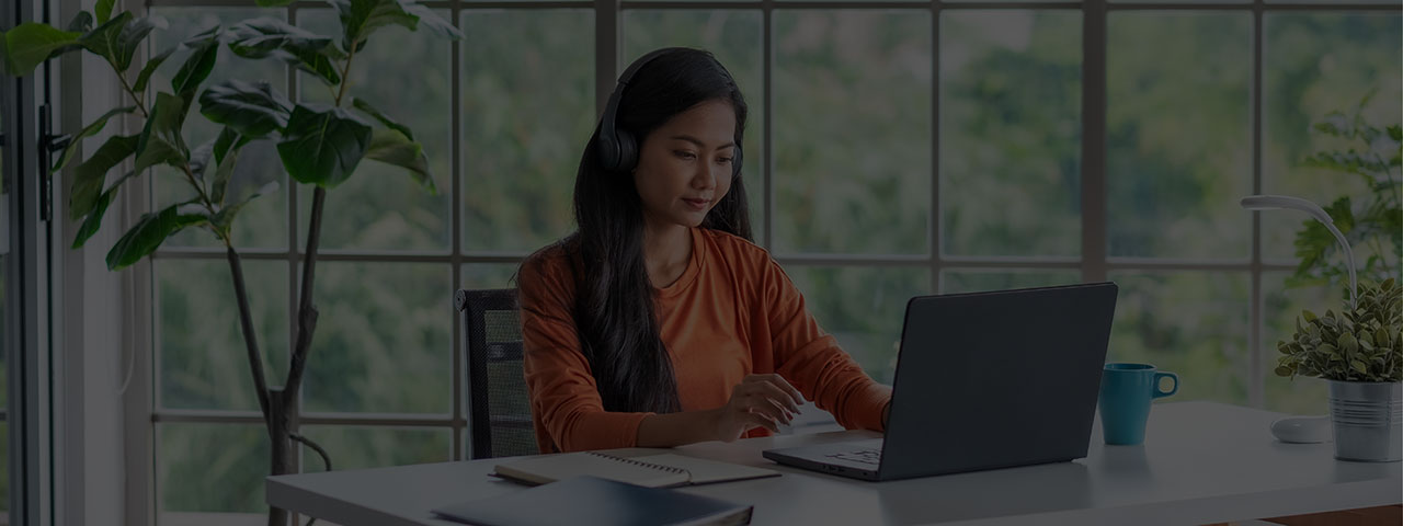 Woman at desk watching a webcast on laptop