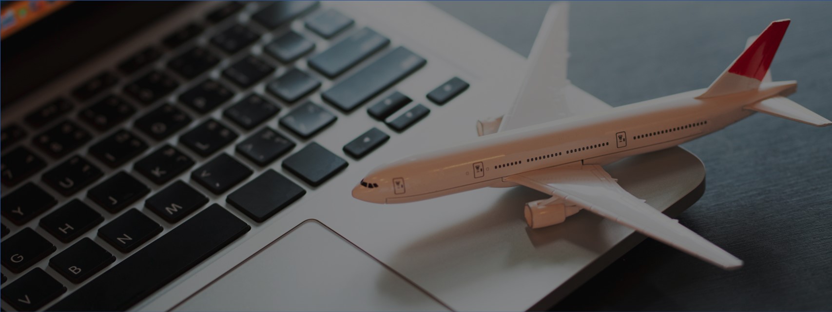 Model airplane sitting on keyboard of laptop computer